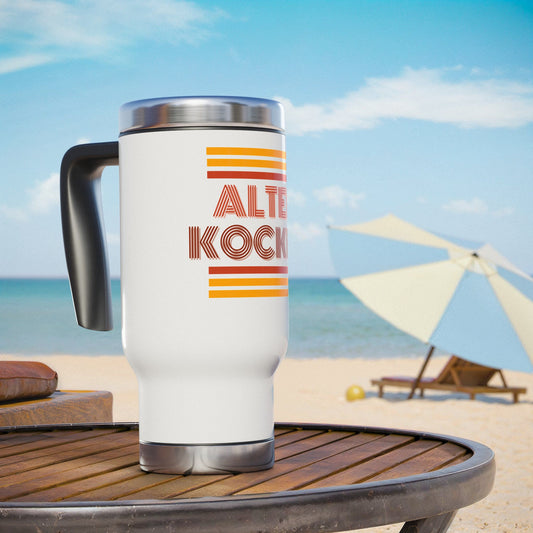 White travel mug with 'ALTER KOCKER' design on a beach setting