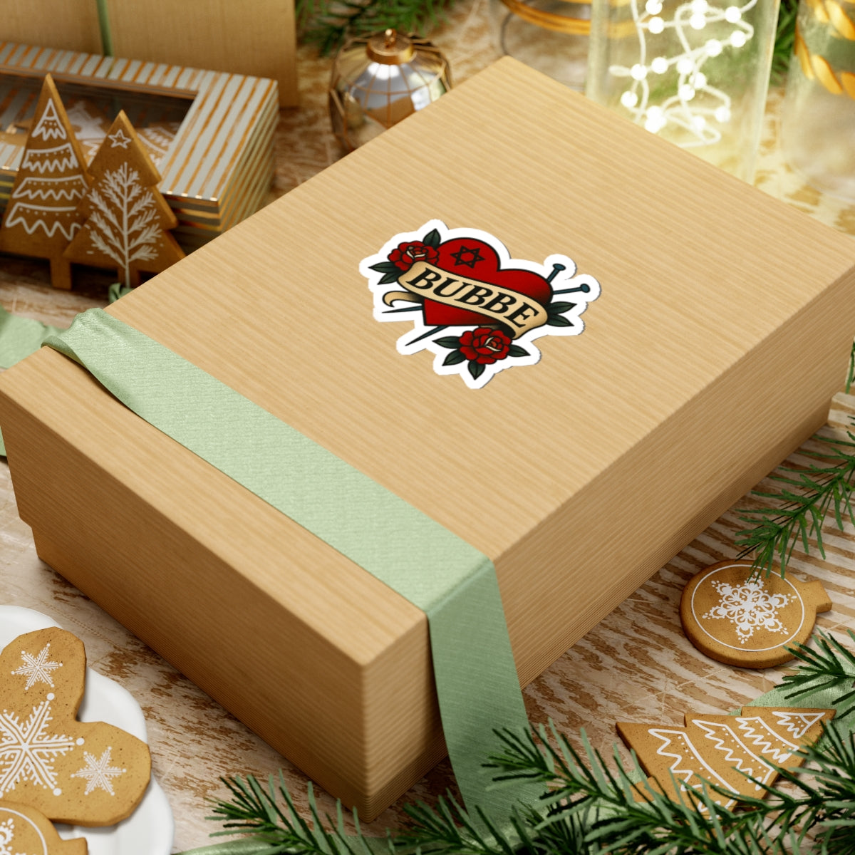 Wooden gift box with a green ribbon and 'Bubbe' sticker, surrounded by Christmas cookies and decorations.