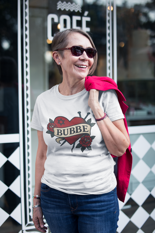 Woman wearing a white t-shirt with a graphic design and text, standing in front of a store entrance.