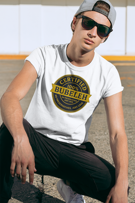 Person wearing a white t-shirt with 'Certified Bubeleh' design, sitting outdoors.