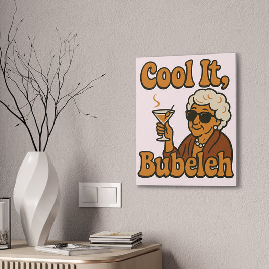 Canvas print with a humorous design of an elderly woman holding a cocktail, text 'Cool It, Bubeleh', on a wall above a table.