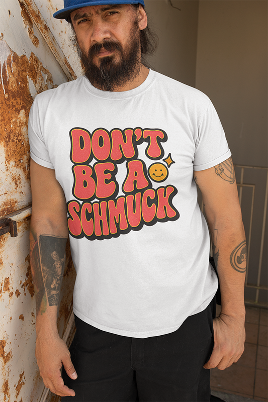 Man wearing a white t-shirt with red text 'Don't be a Schmuck' standing against a wall.
