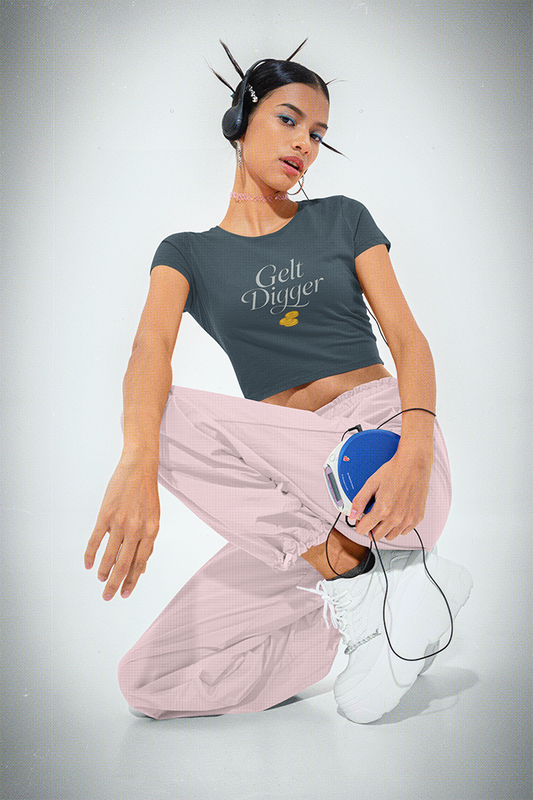 Woman wearing a 'Gelt Digger' t-shirt and pink pants on a gray background