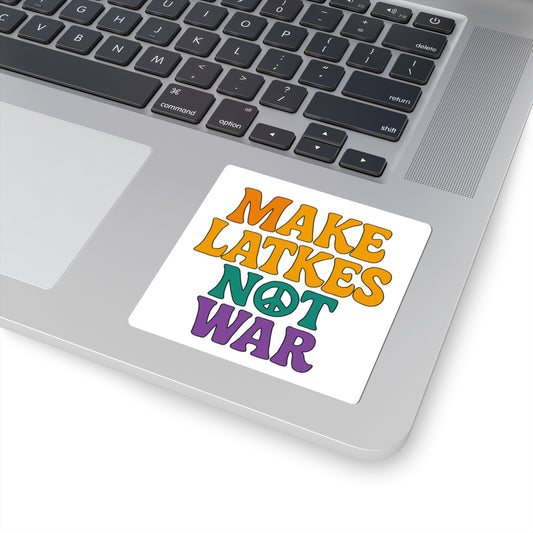 Laptop with a sticker reading 'Make Latkes Not War' on a white surface