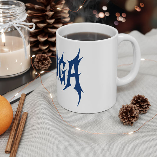 White mug with blue 'meshuga' design on a table with decorative items