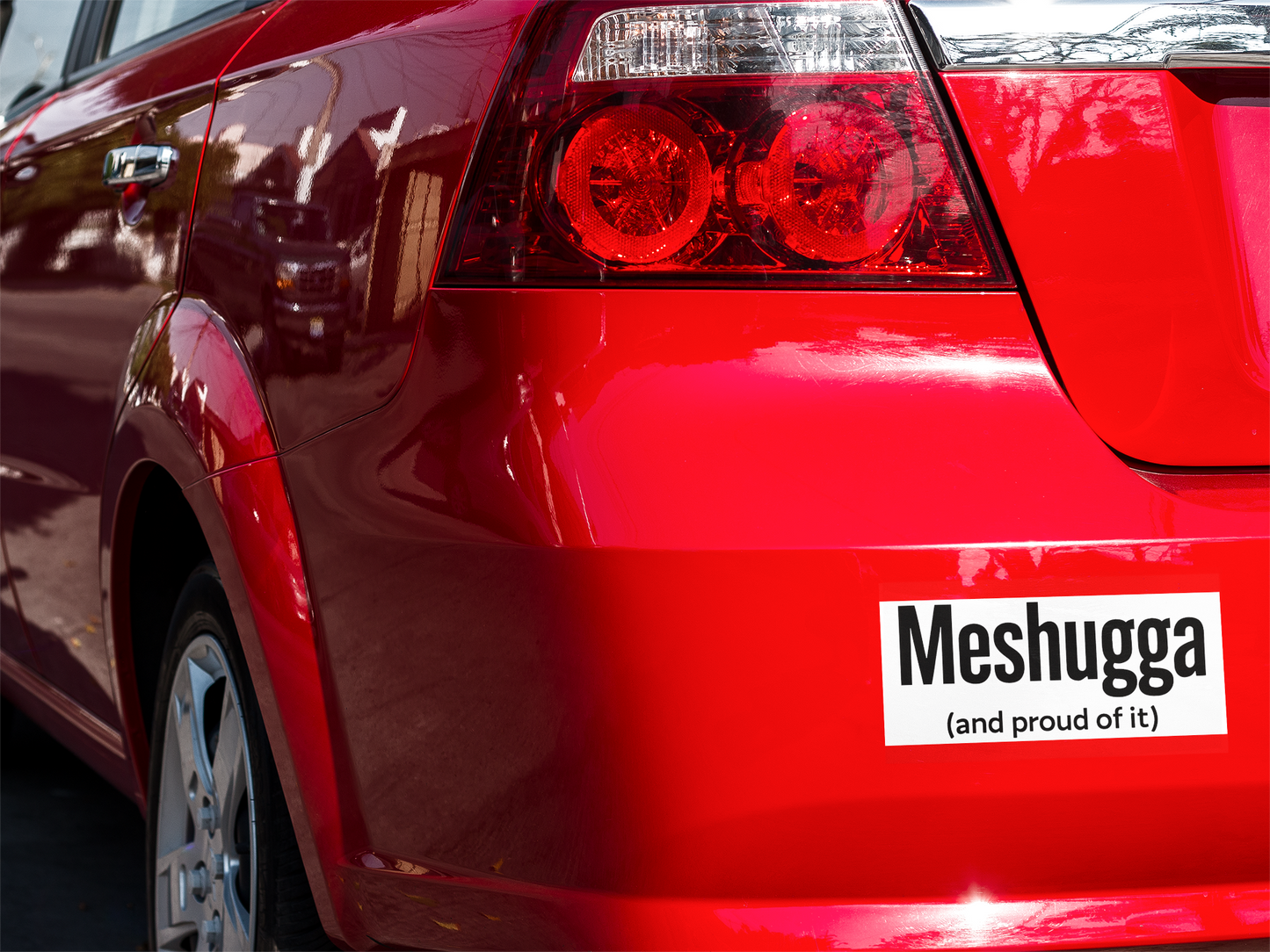 Red car with a 'Meshugga (and proud of it)' sticker on the back