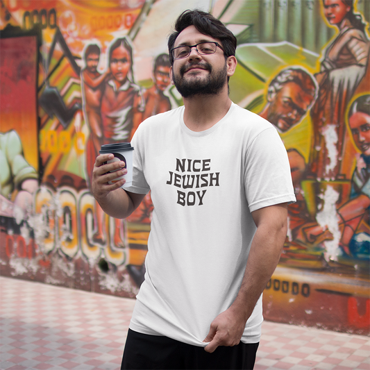 Man wearing a white t-shirt with 'Nice Jewish Boy' text, holding a coffee cup, in front of a colorful mural.
