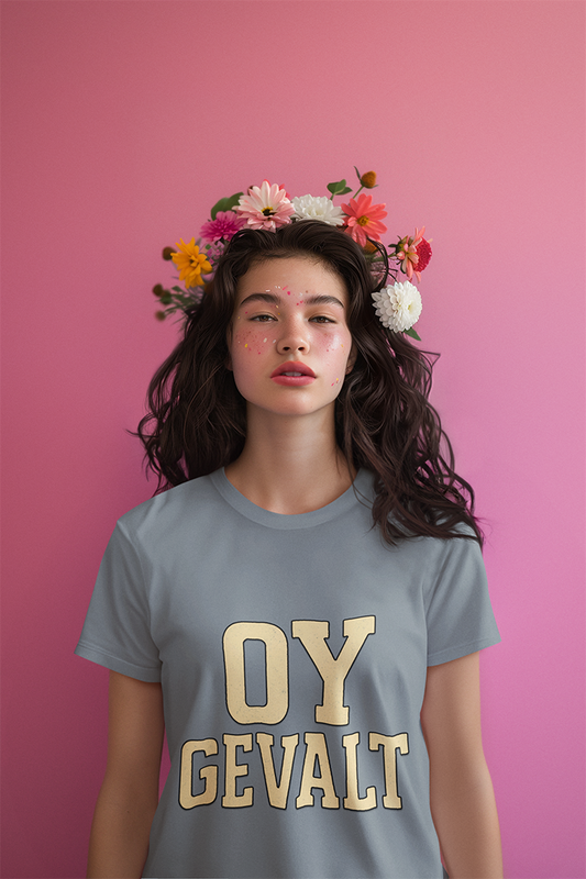 Person wearing a gray t-shirt with 'OY GEVALT' in gold letters against a pink background