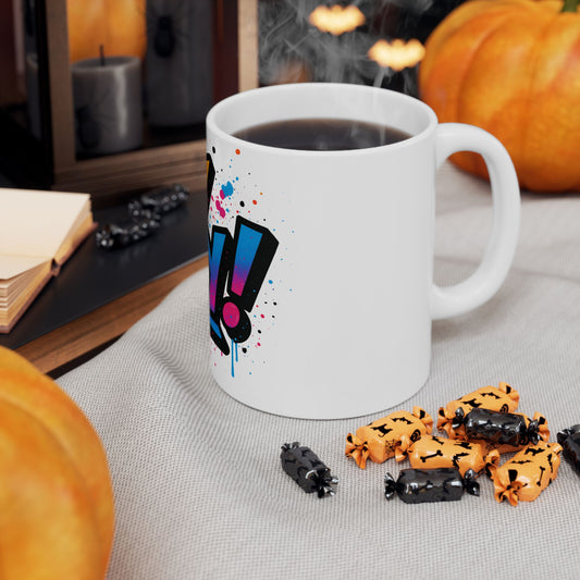 White mug with colorful 'oy vey' design on a table with Halloween-themed treats and pumpkins.