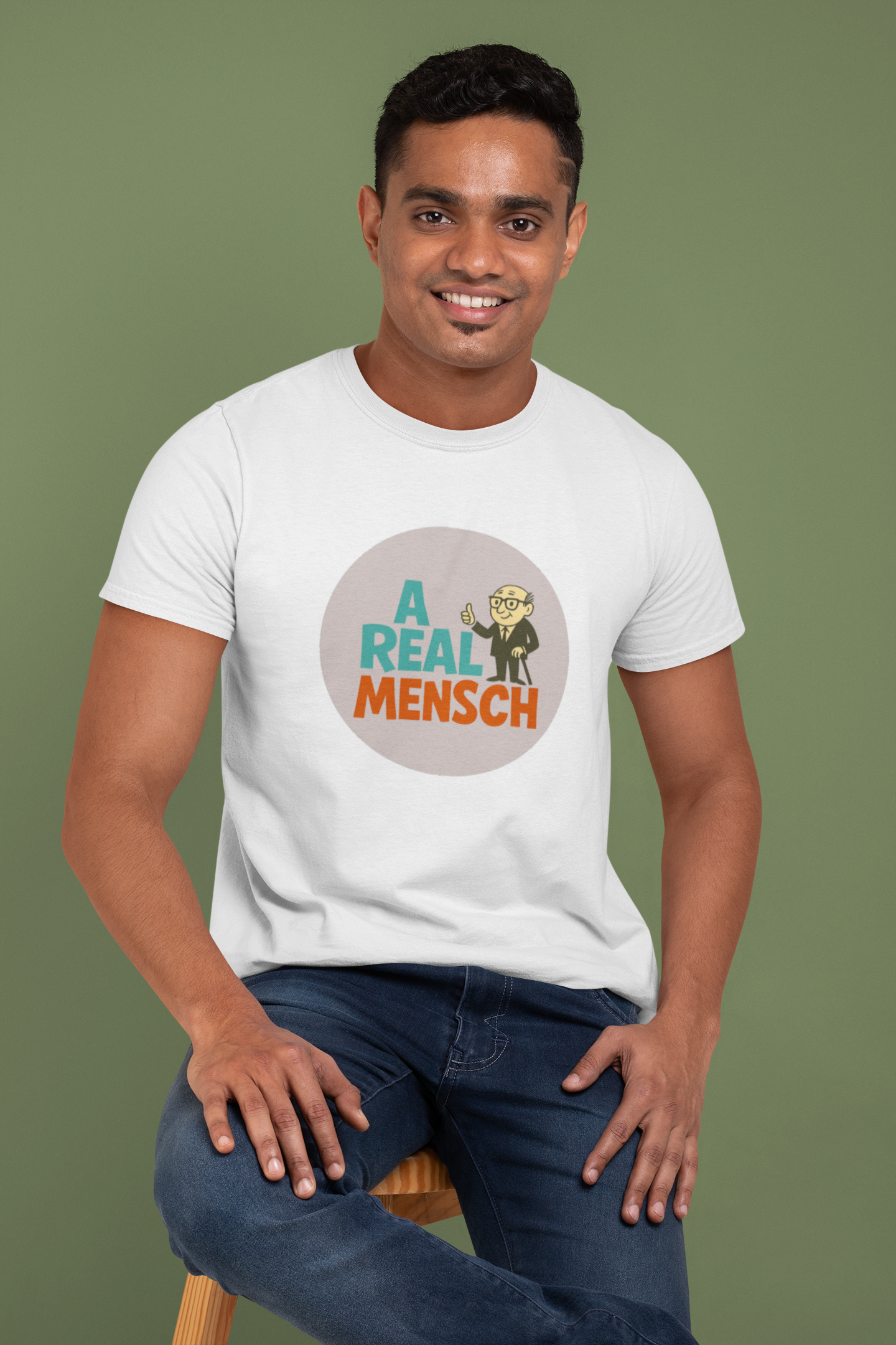 Man wearing a white t-shirt with a graphic design and text, sitting on a stool against a green background