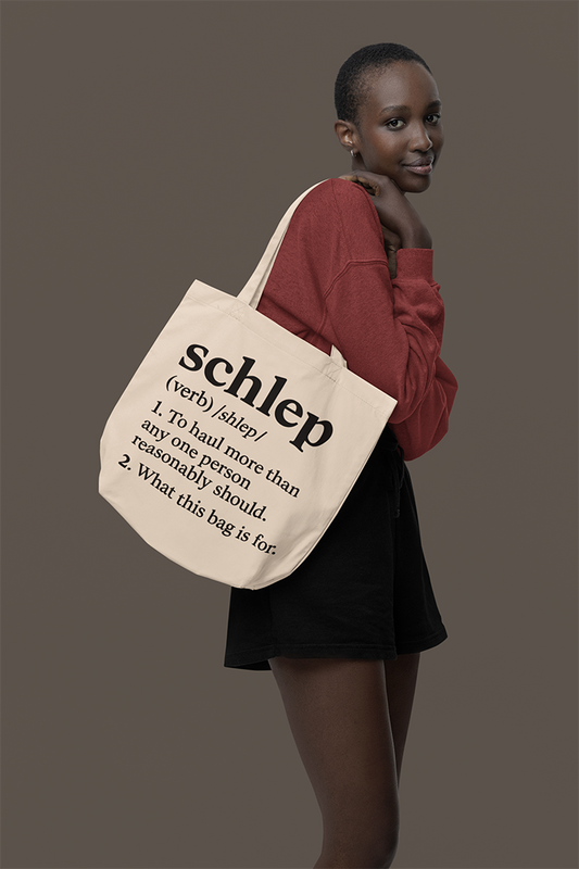 Woman holding a tote bag with text design against a plain background
