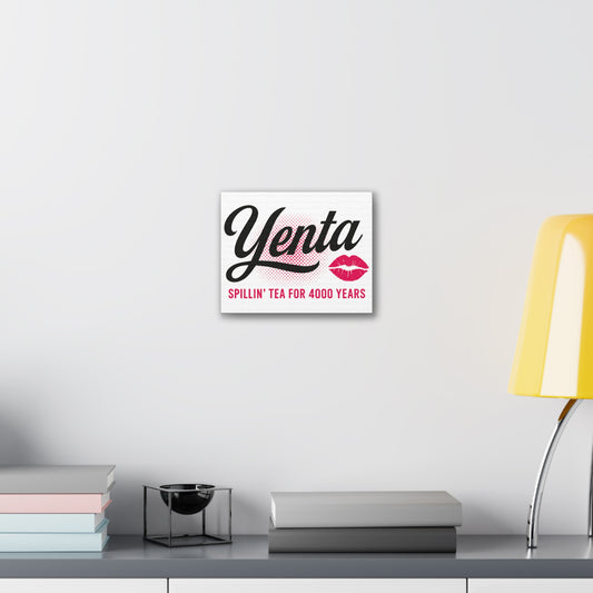 Decorative sign with 'Yenta' text on a wall above a desk with books and a lamp.