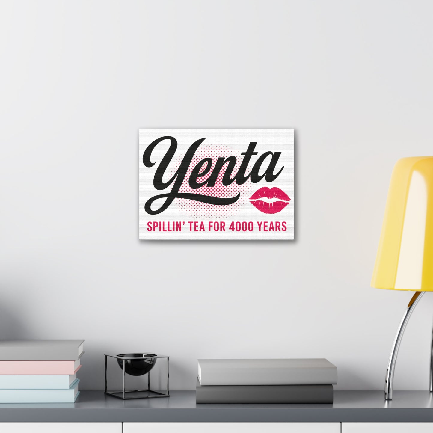Framed artwork with 'Yenta' text and lip prints on a white wall above a desk.