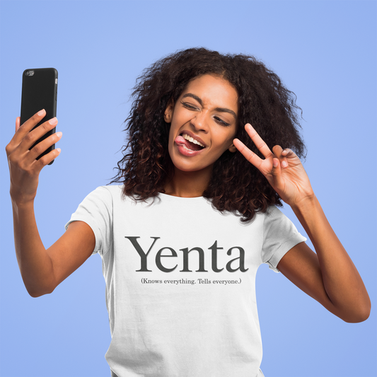 Woman wearing a 'Yenta' t-shirt, making a peace sign and holding a phone against a blue background