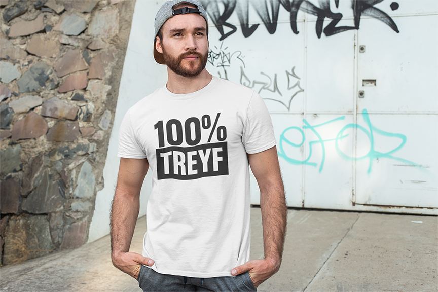 Man wearing a white t-shirt with '100% TREYF' text standing against a graffiti-covered wall.