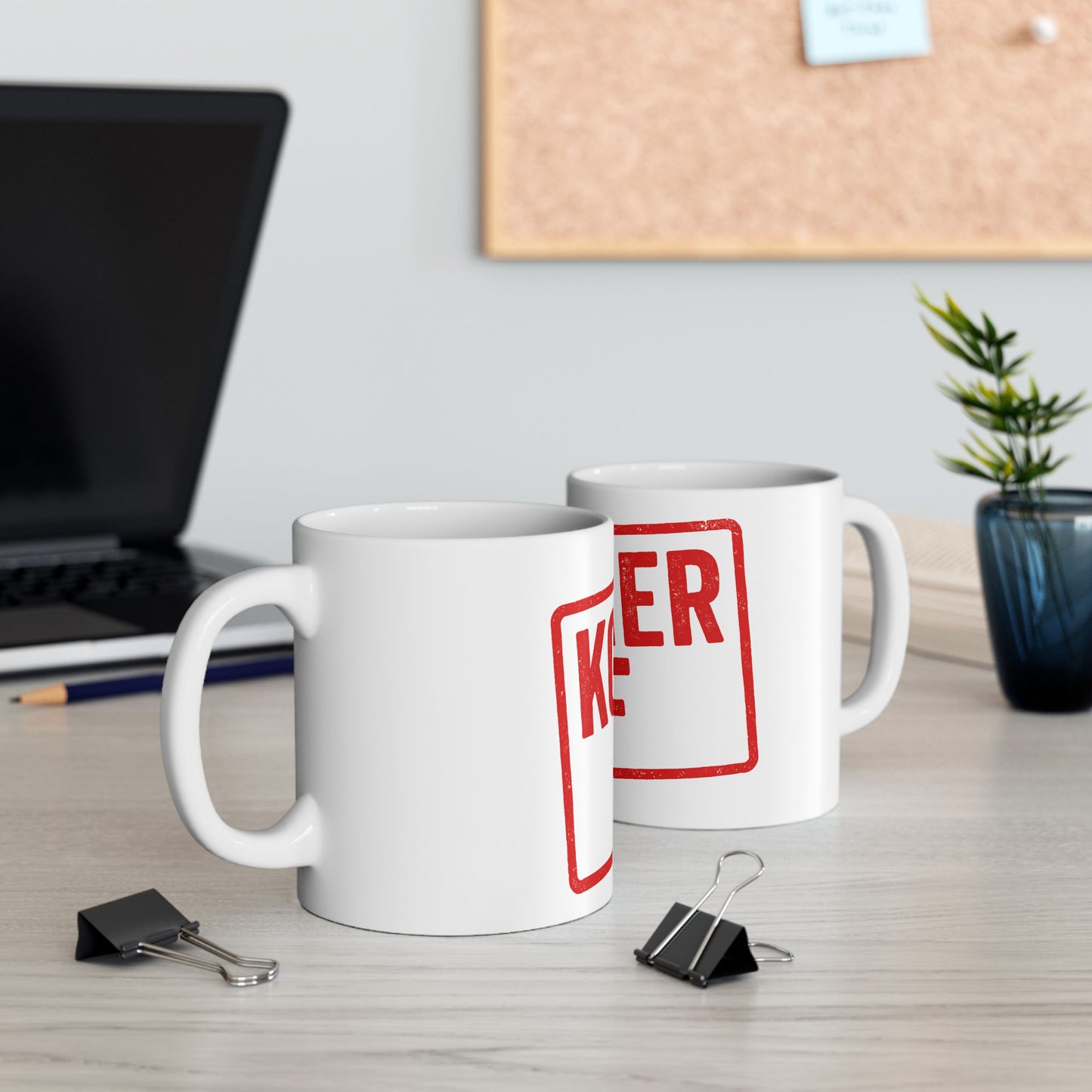 Two white mugs with 'kosher af' in red text on a desk with office supplies and a plant.