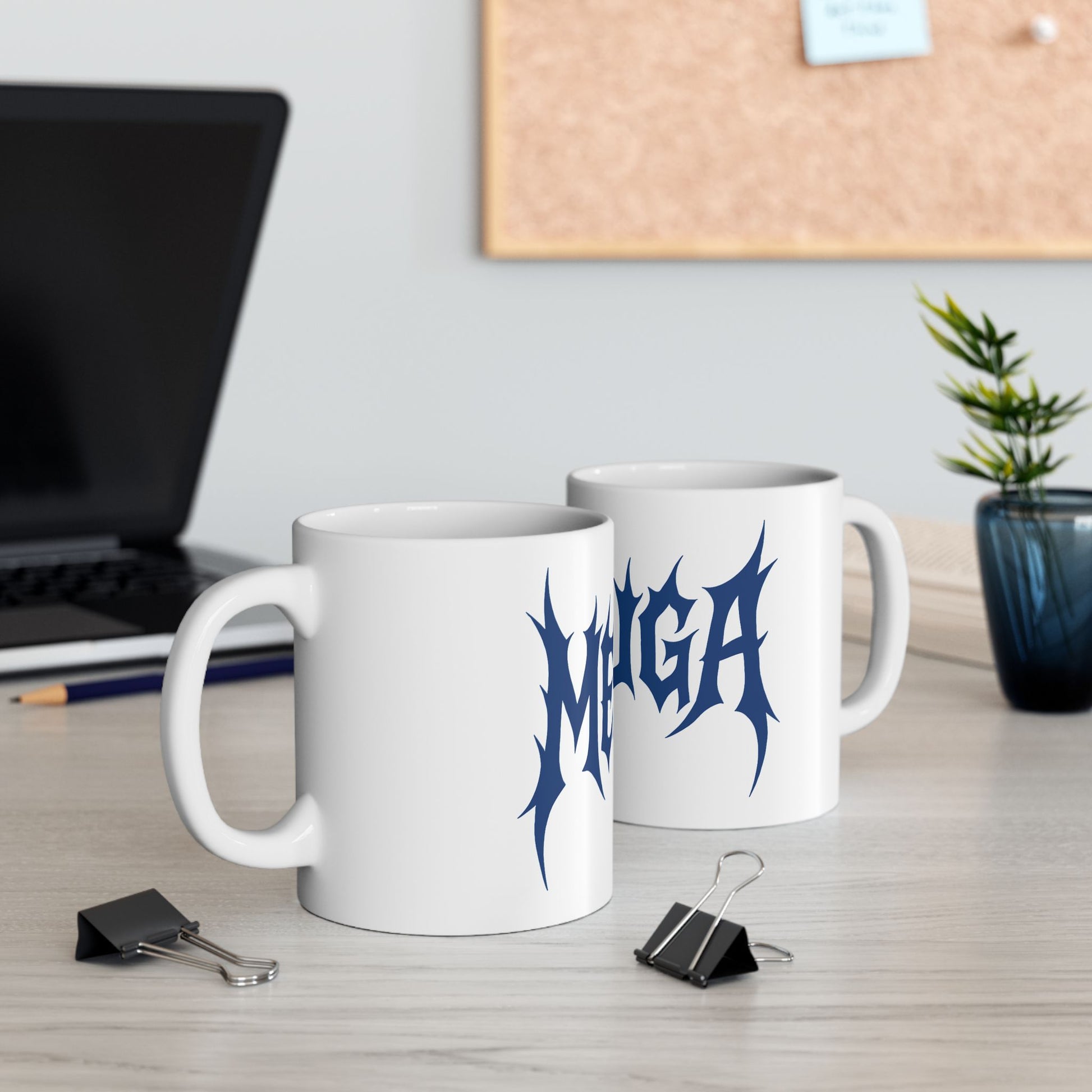 Two white mugs with blue 'meshuga' design on a desk with office supplies.