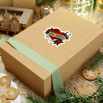 Wooden gift box with a green ribbon and 'Bubbe' sticker, surrounded by Christmas cookies and decorations.