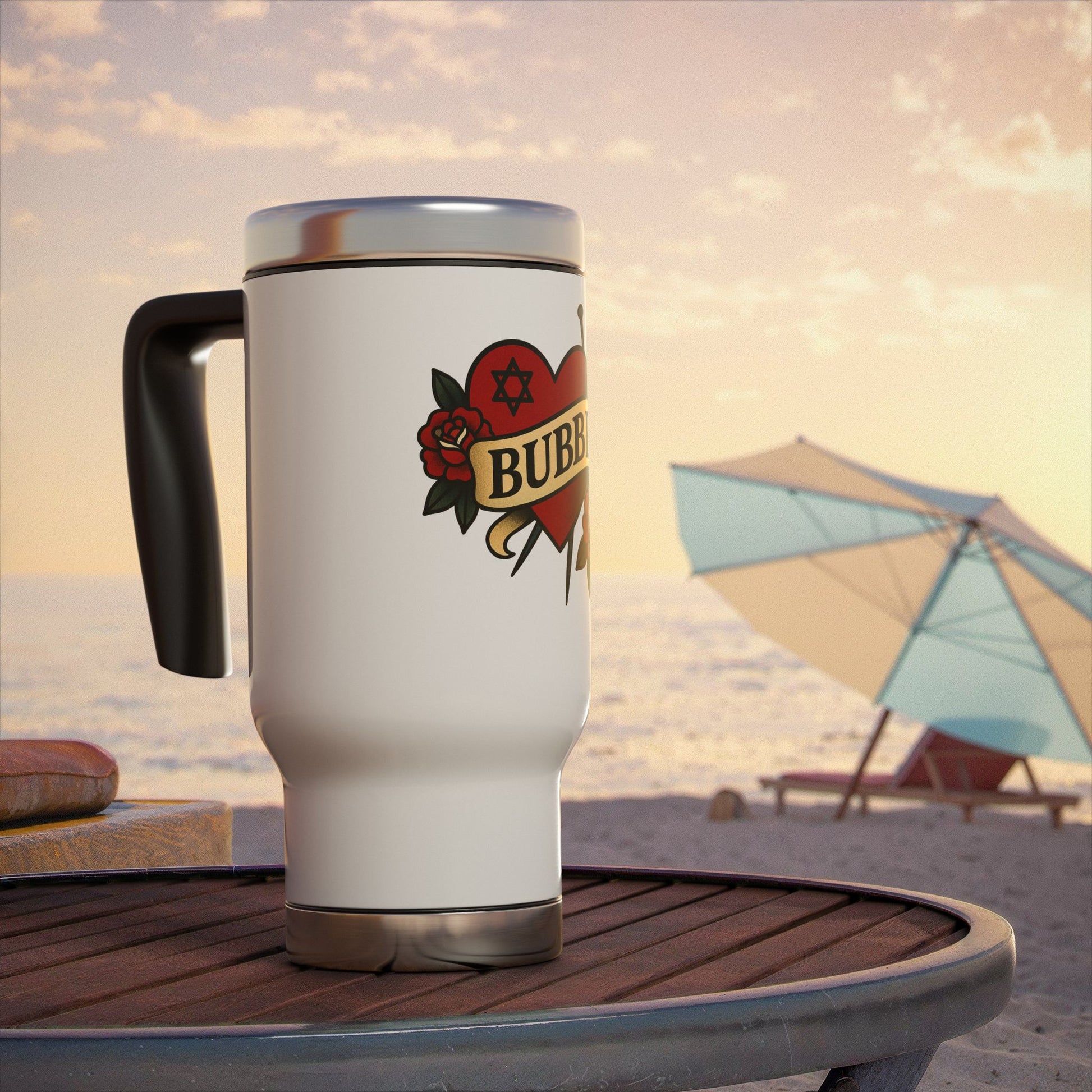 White travel mug with a tattoo-style design on a beach table with an umbrella in the background