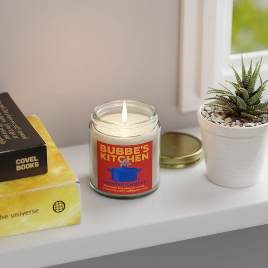 Candle labeled 'Bubbe's Kitchen' on a shelf with books and a plant