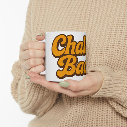Person holding a mug with 'Challah Back' text in yellow and brown, wearing a beige sweater.