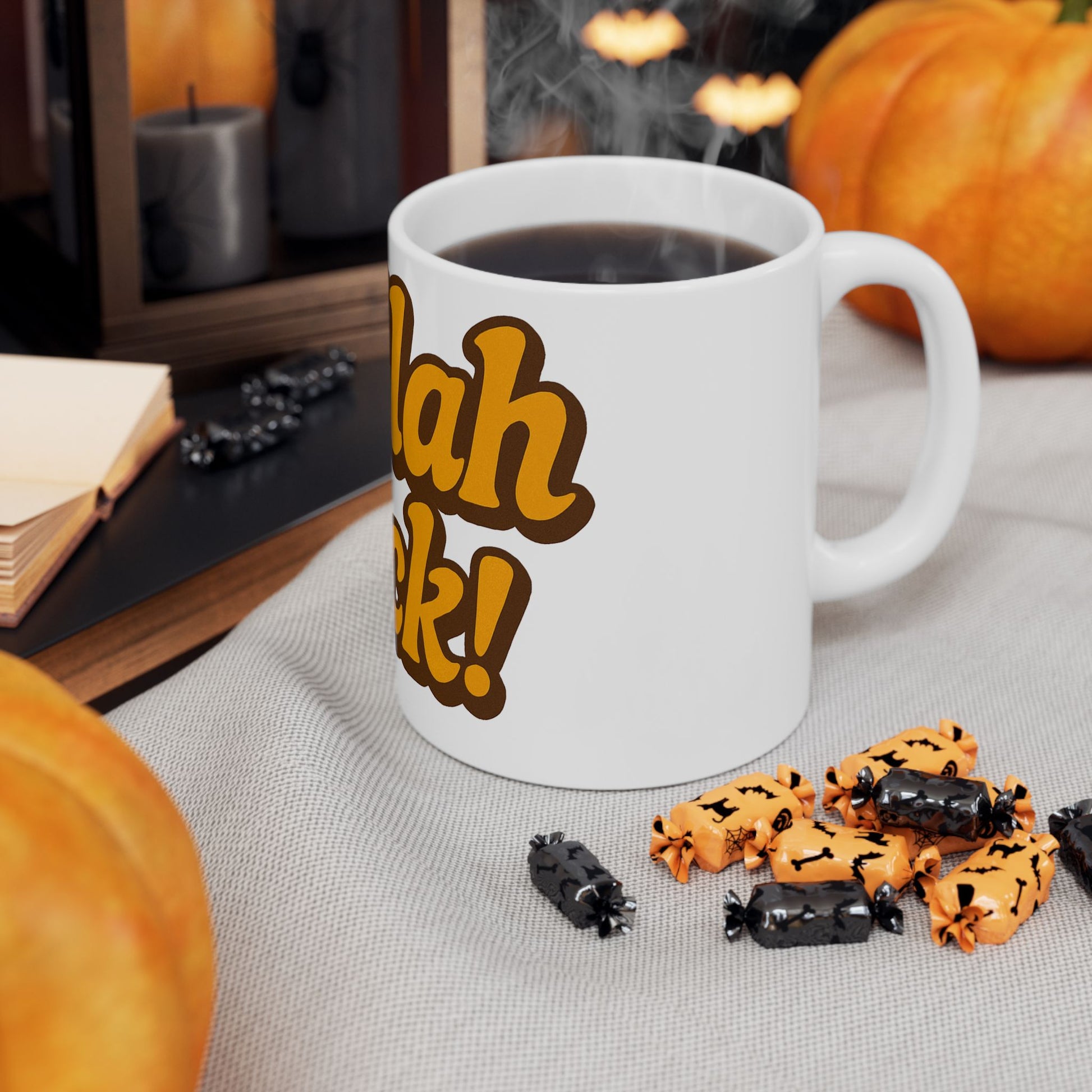 White mug with 'Challah Back!' text, Halloween-themed treats, and pumpkins on a table.