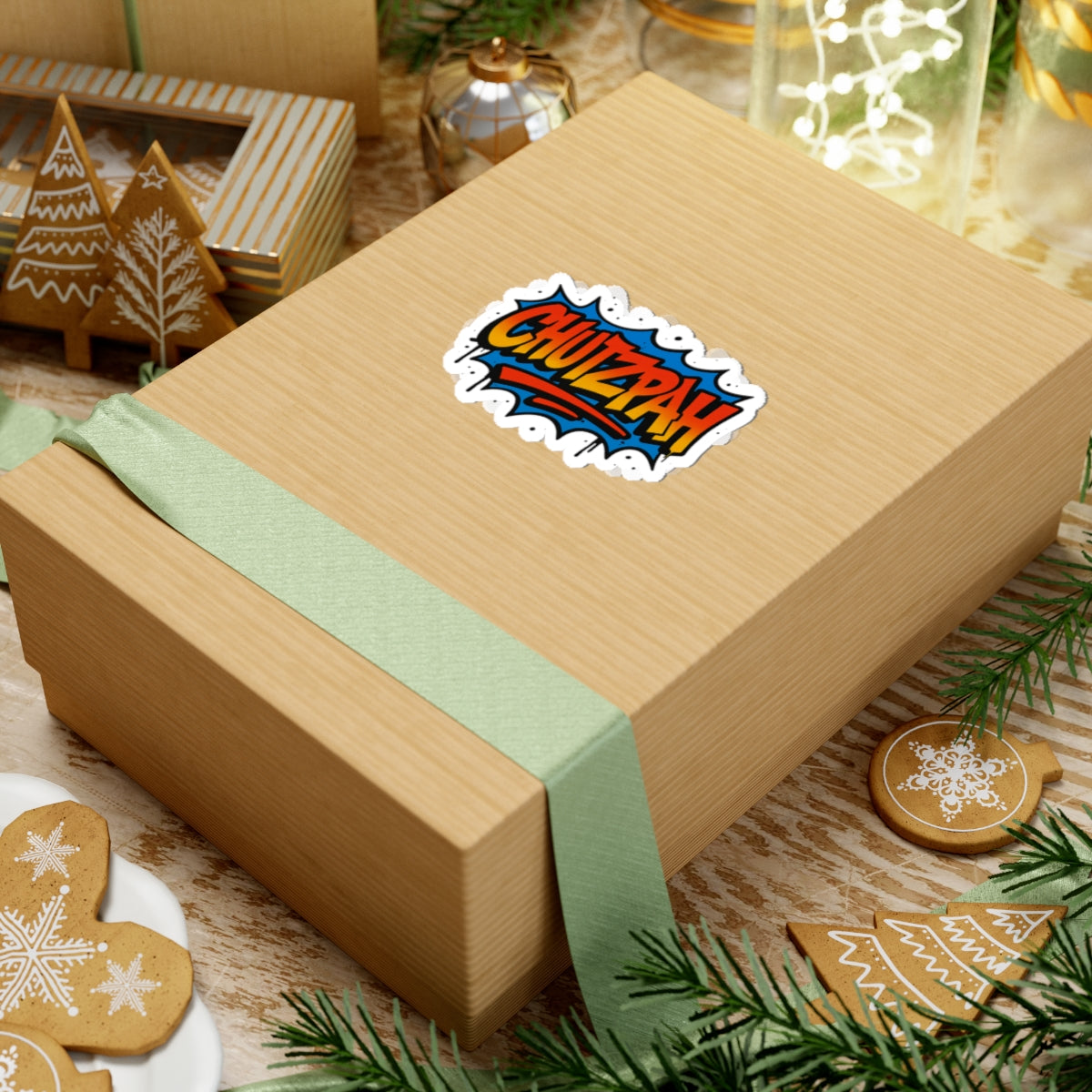 Gift box with a 'CHUZPAH' sticker on a festive background with cookies and greenery