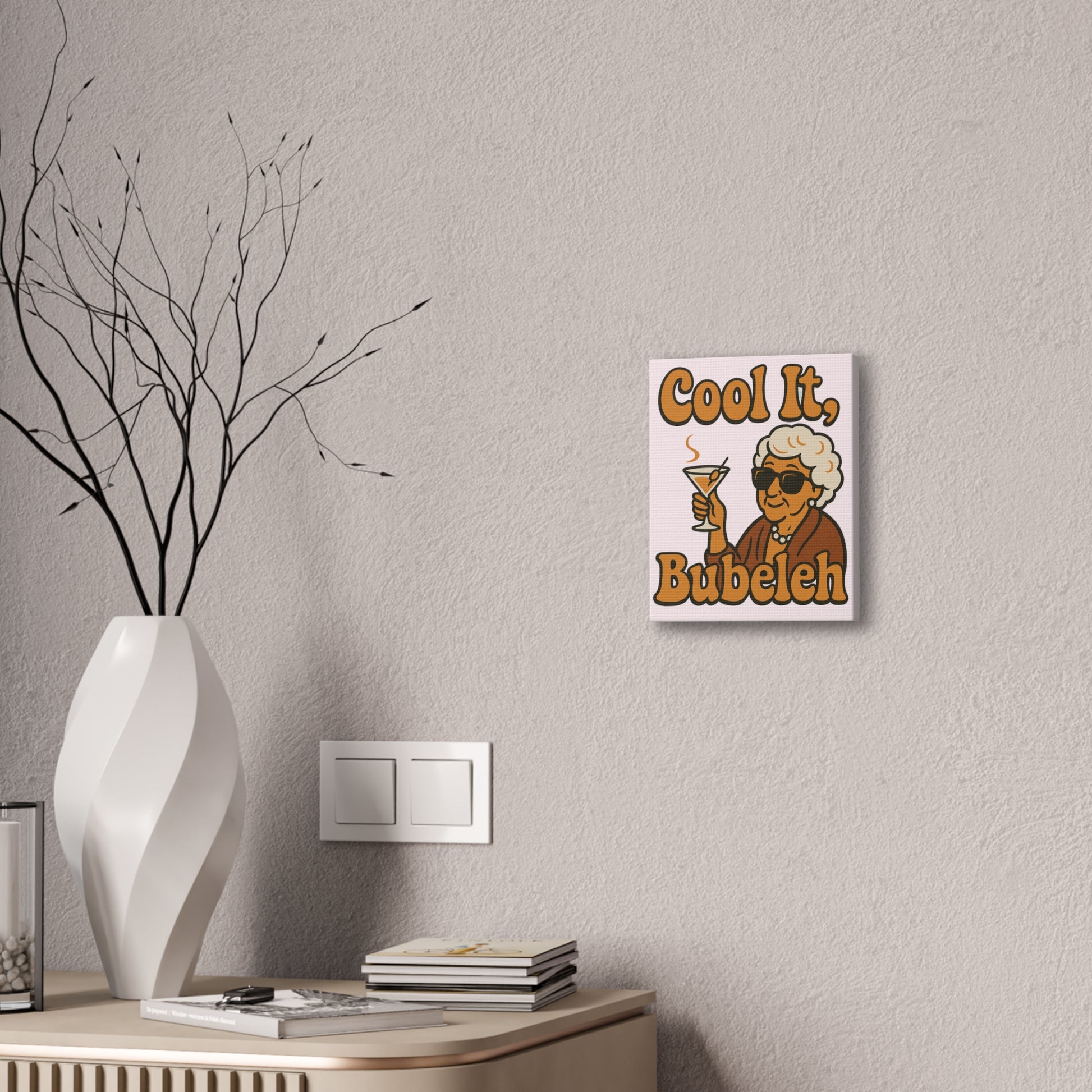 Decorative wall art with a character and text 'Cool It, Bubeleh' on a gray wall above a desk.