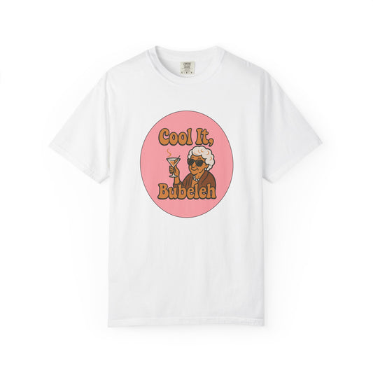 White t-shirt with a graphic design of an older woman holding a martini glass and text 'Cool It, Bubeleh' on a pink circle, against a white background.