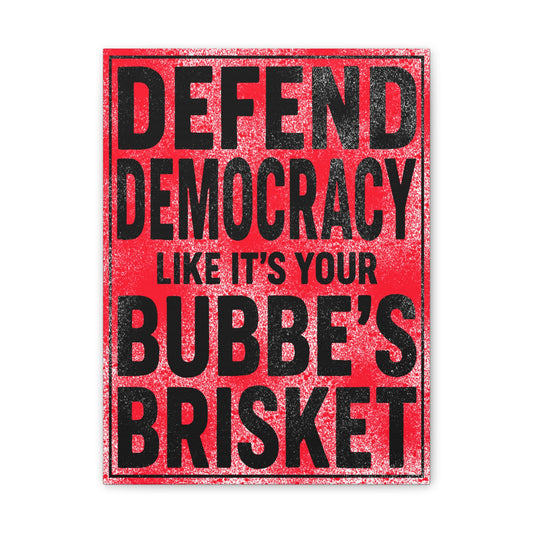 Red sign with black text reading 'Defend Democracy Like It's Your Bubbe's Brisket' on a white background