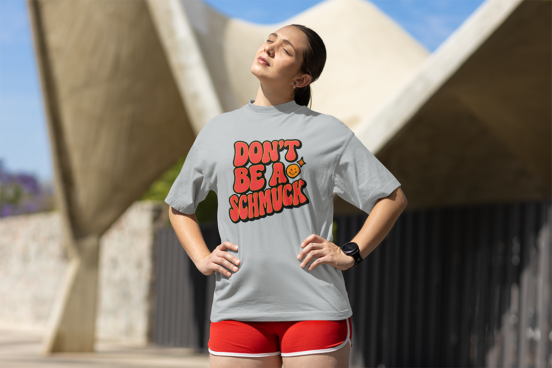 Woman wearing a gray t-shirt with a colorful text design outdoors.