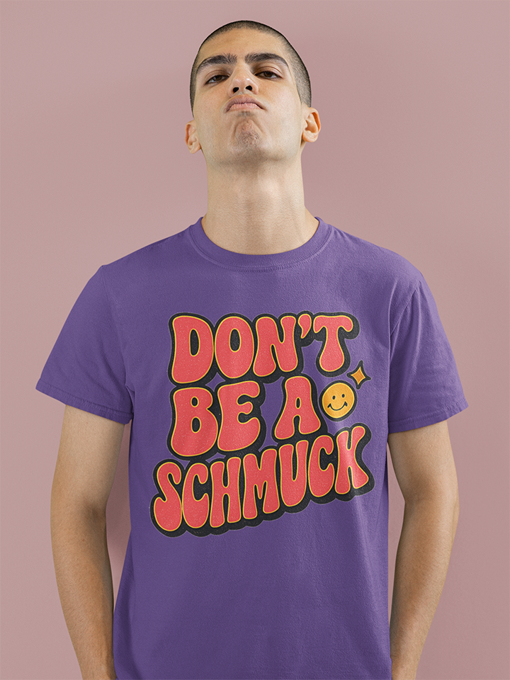 Person wearing a purple t-shirt with red text and a smiley face on a pink background