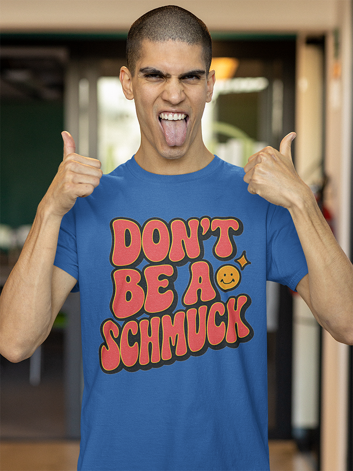 Person wearing a blue t-shirt with 'DON'T BE A SCHMUCK' text, giving thumbs up indoors.