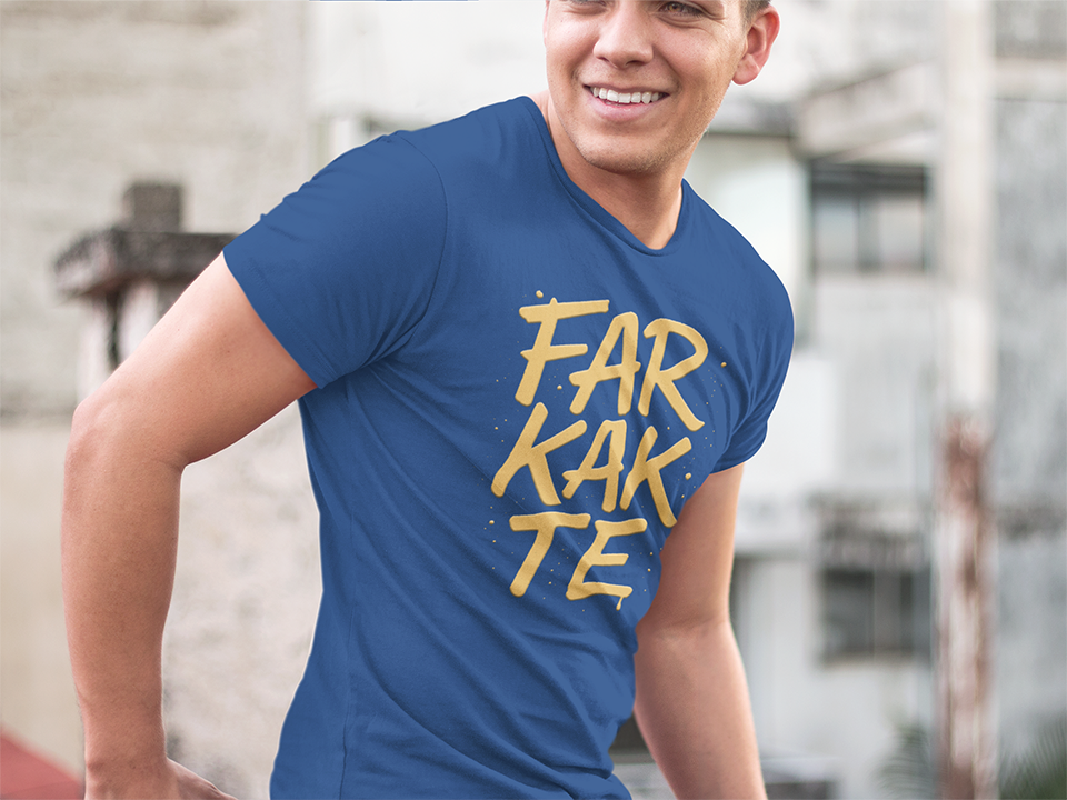 Man wearing a blue t-shirt with yellow text 'FARKATE' outdoors.