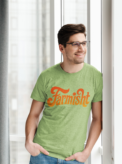 Man wearing a green t-shirt with 'Farmisht' printed on it, standing indoors.