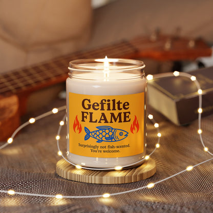 Candle in a jar labeled 'Gefilte Flame' with a fish design, surrounded by string lights on a wooden surface.
