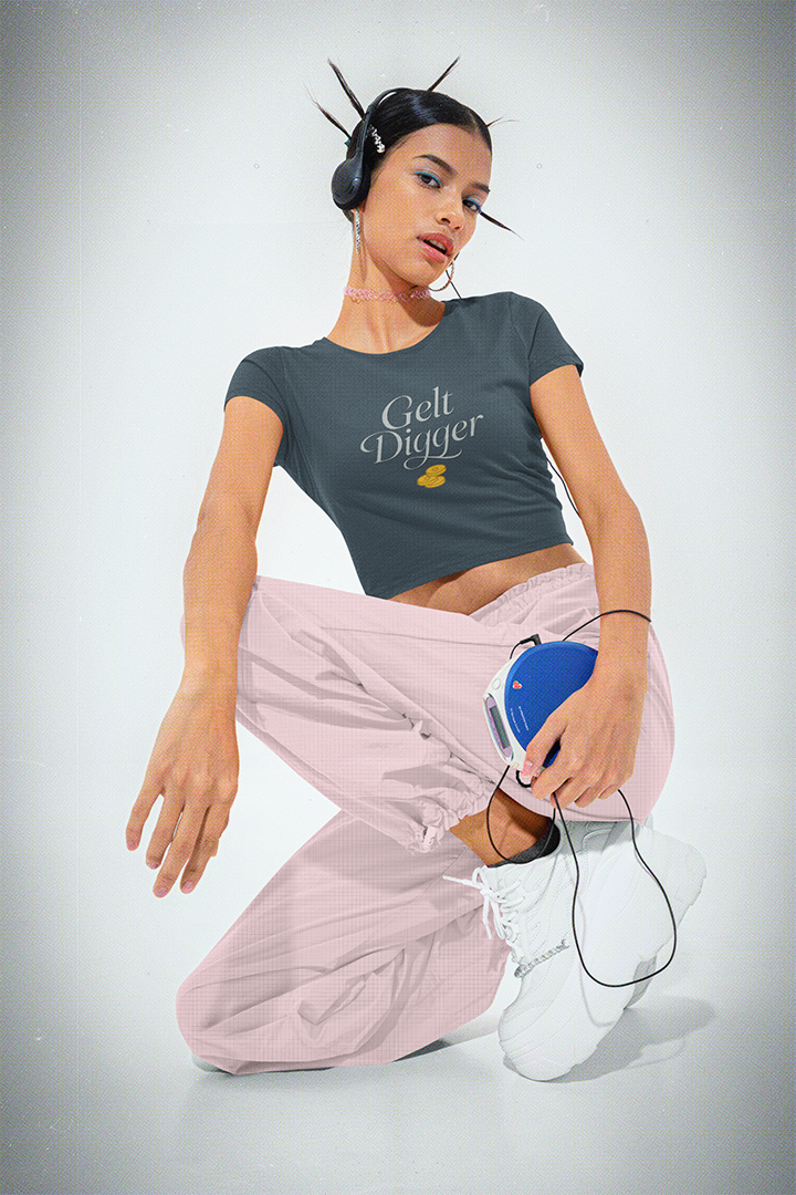 Woman wearing a 'Gelt Digger' t-shirt and pink pants on a gray background