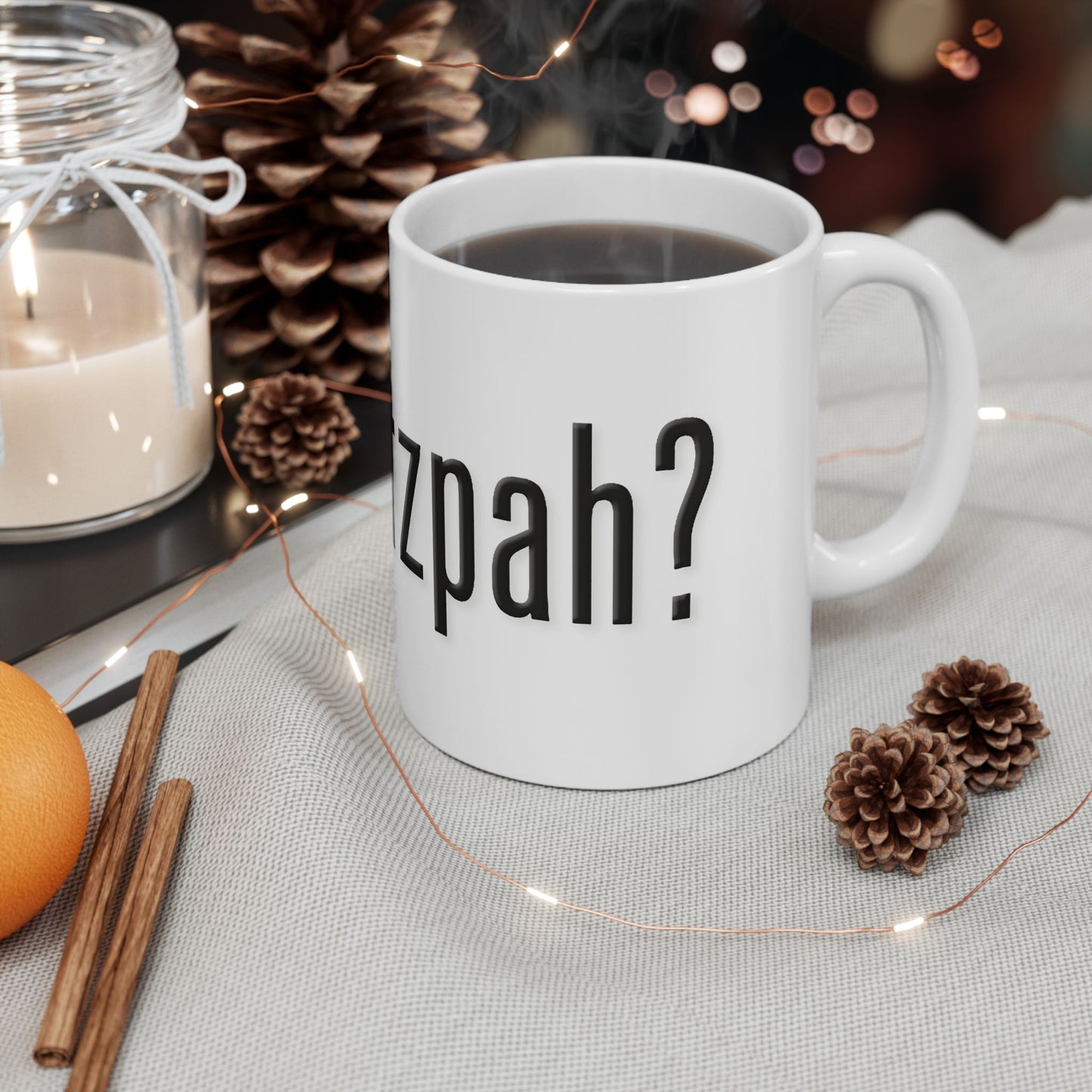 White mug with 'got chutzpah?' text on a table with decorative items