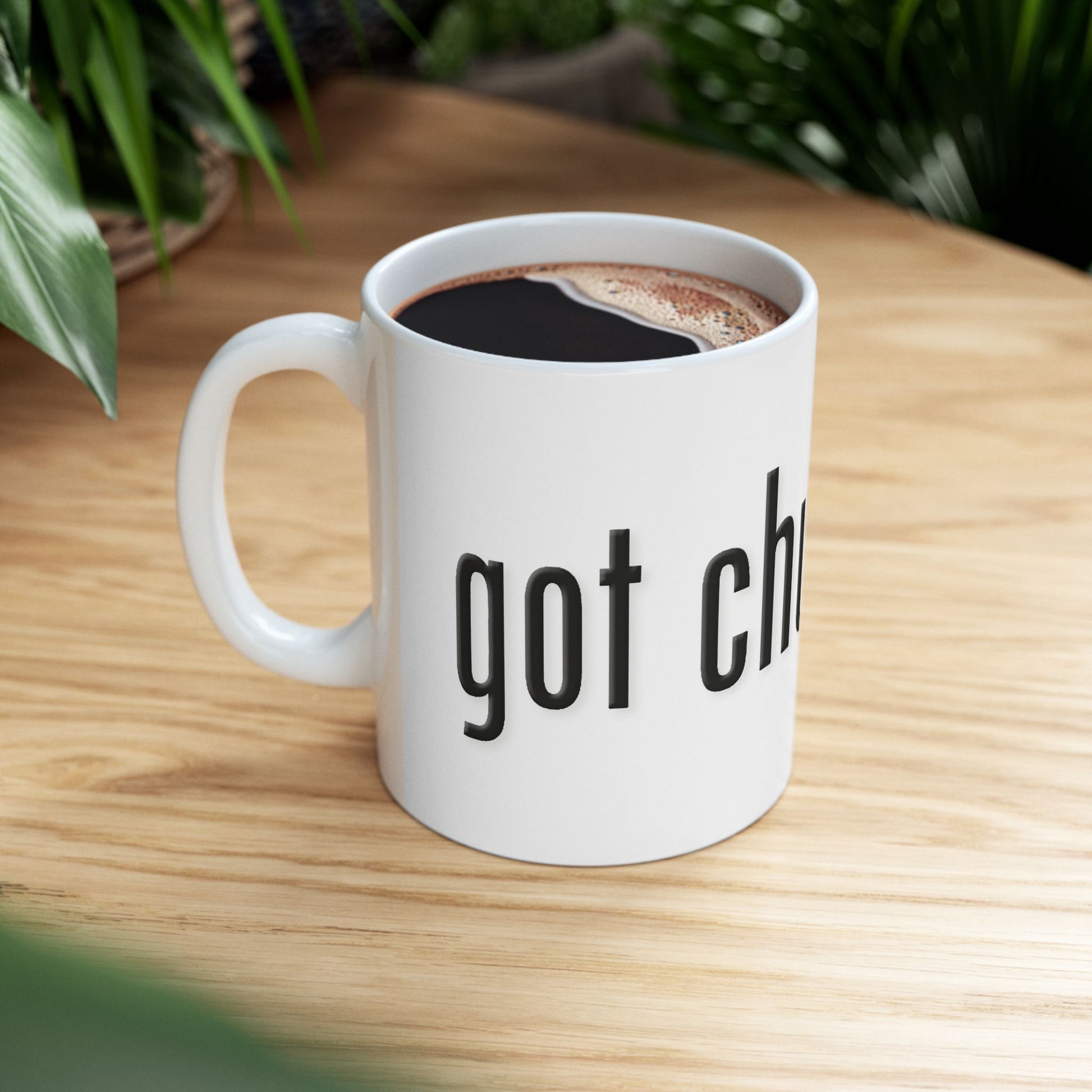 White mug with 'got chutzpah?' text on a wooden table with coffee.
