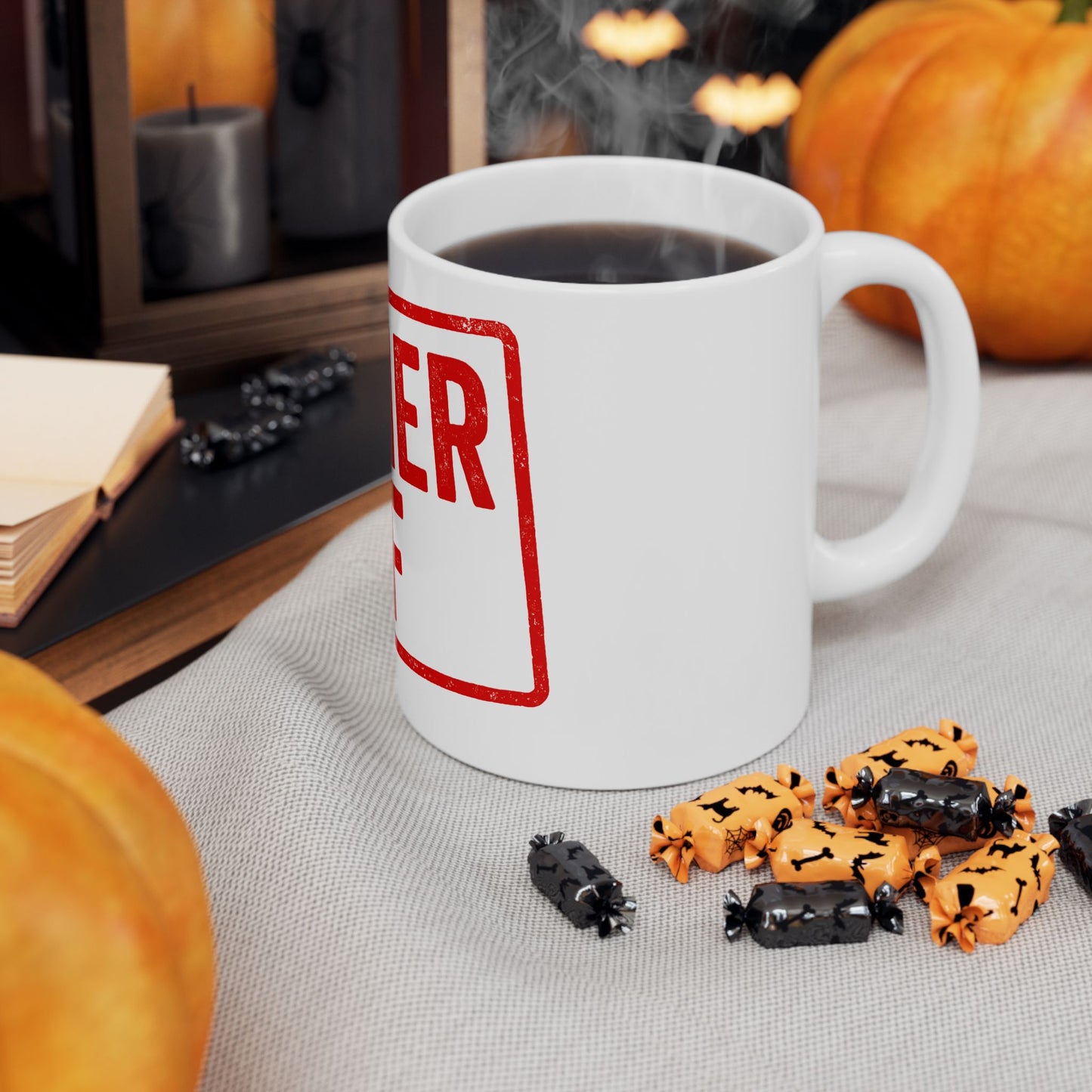 White mug with 'kosher af' in red text, steaming hot chocolate, Halloween-themed cookies, and pumpkins on a table.
