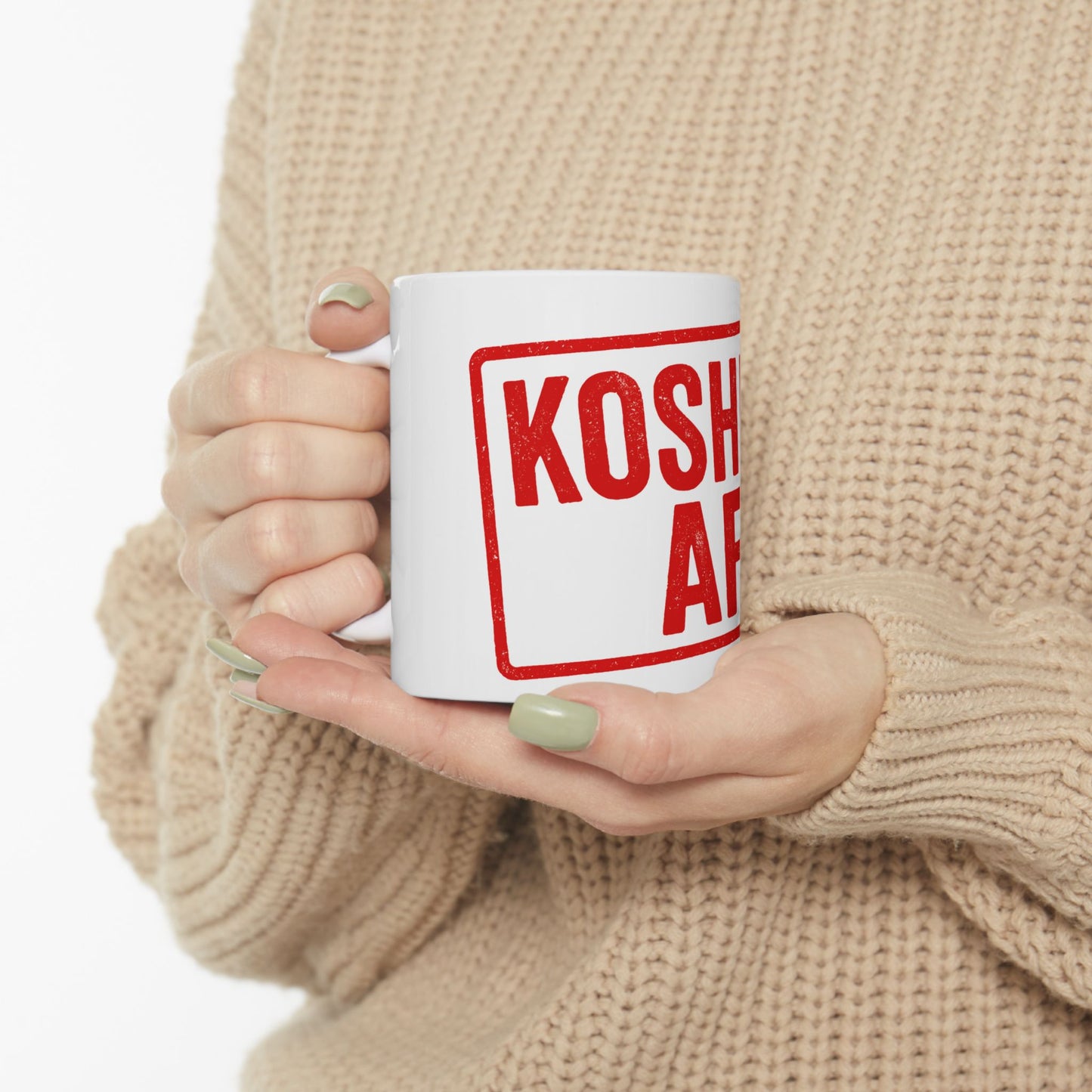 Person holding a white mug with 'kosher af' printed in red on a beige background
