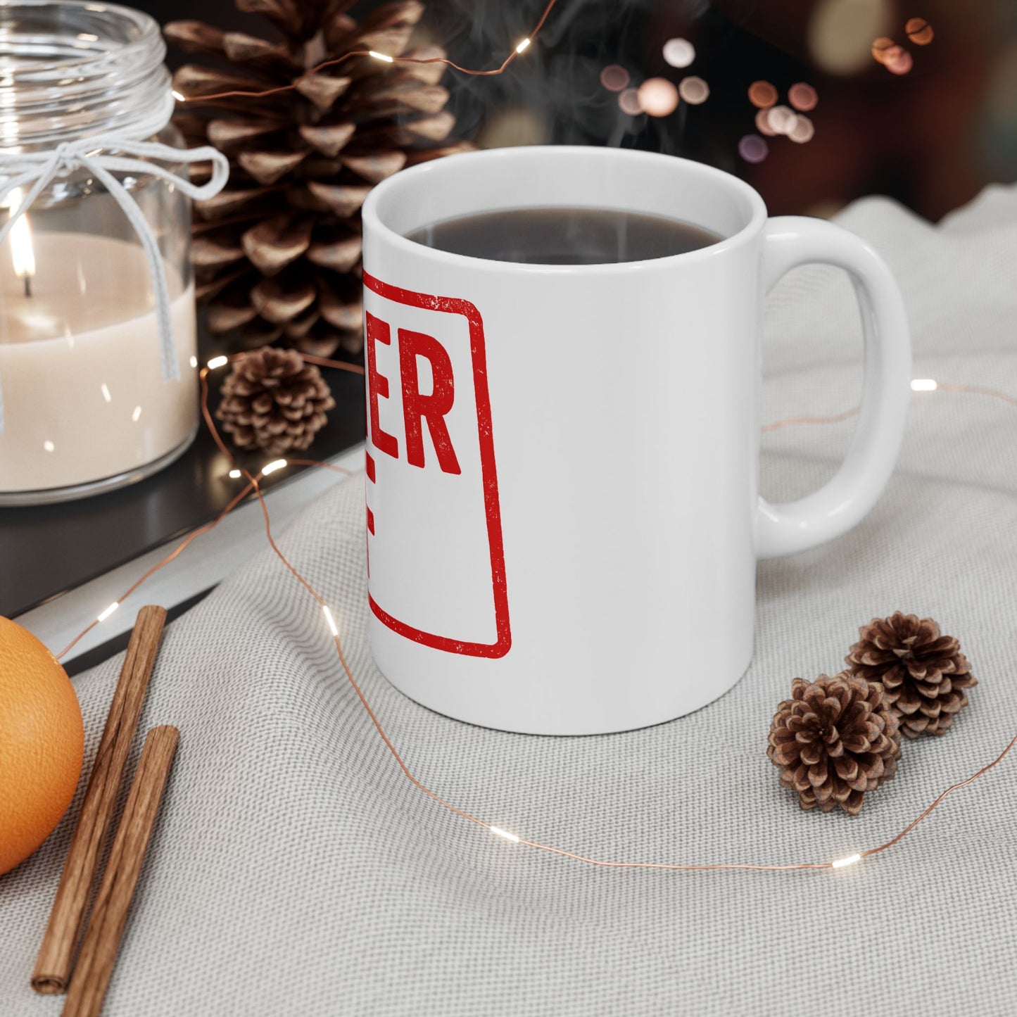 White mug with 'kosher af' in red text on a table with decorative items