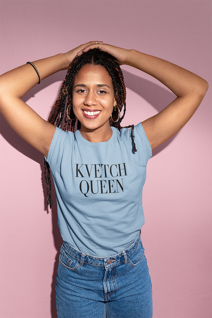 Person wearing a blue t-shirt with 'KVETCH QUEEN' text against a pink background