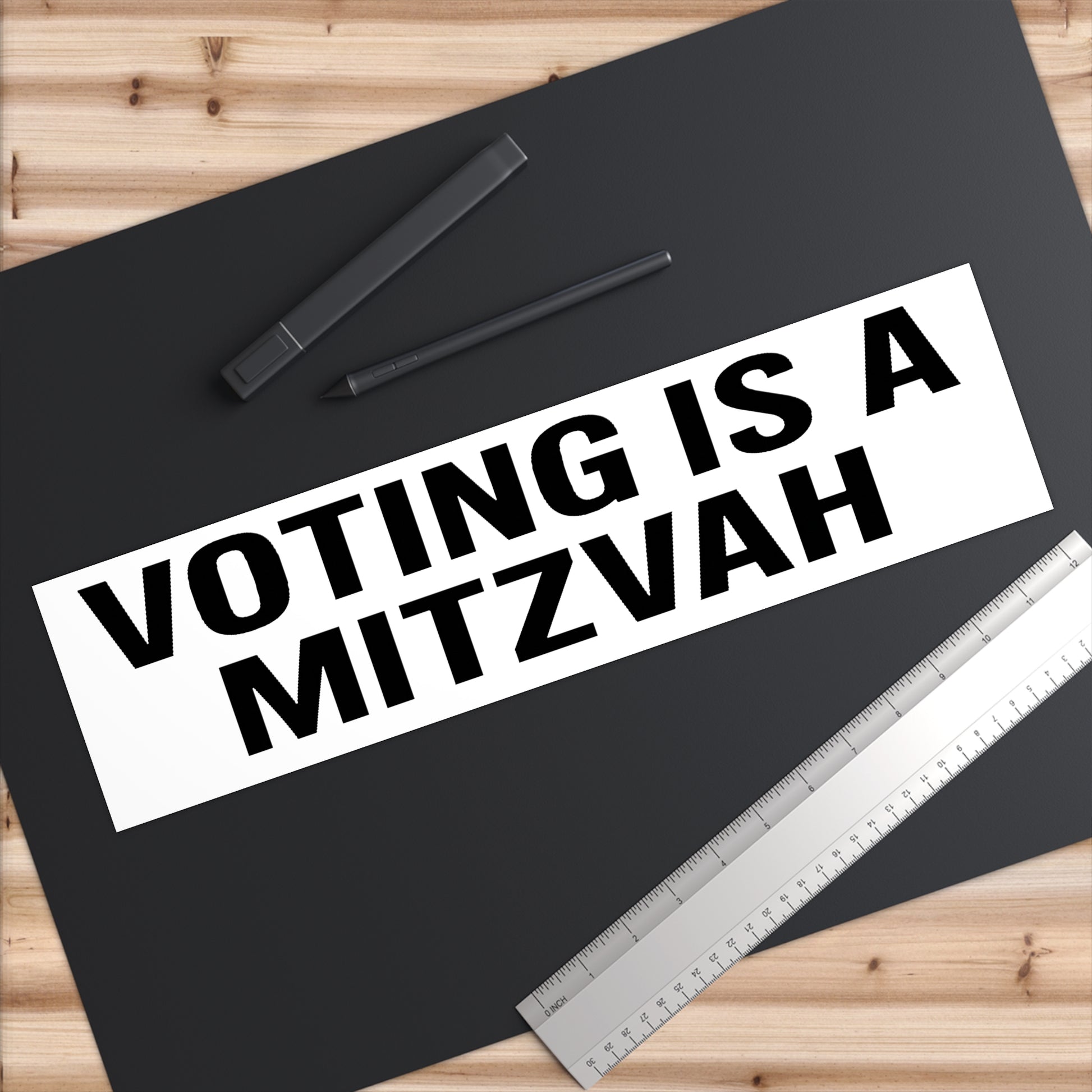 Poster with 'Voting is a Mitzvah' text on a black background with a pen and ruler.