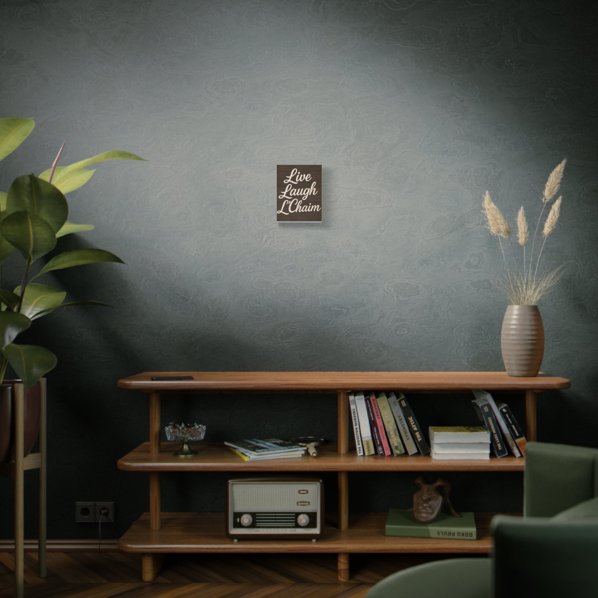 Living room with wooden shelf, books, plant, and decorative 'live laugh l'chaim' print against a dark wall.