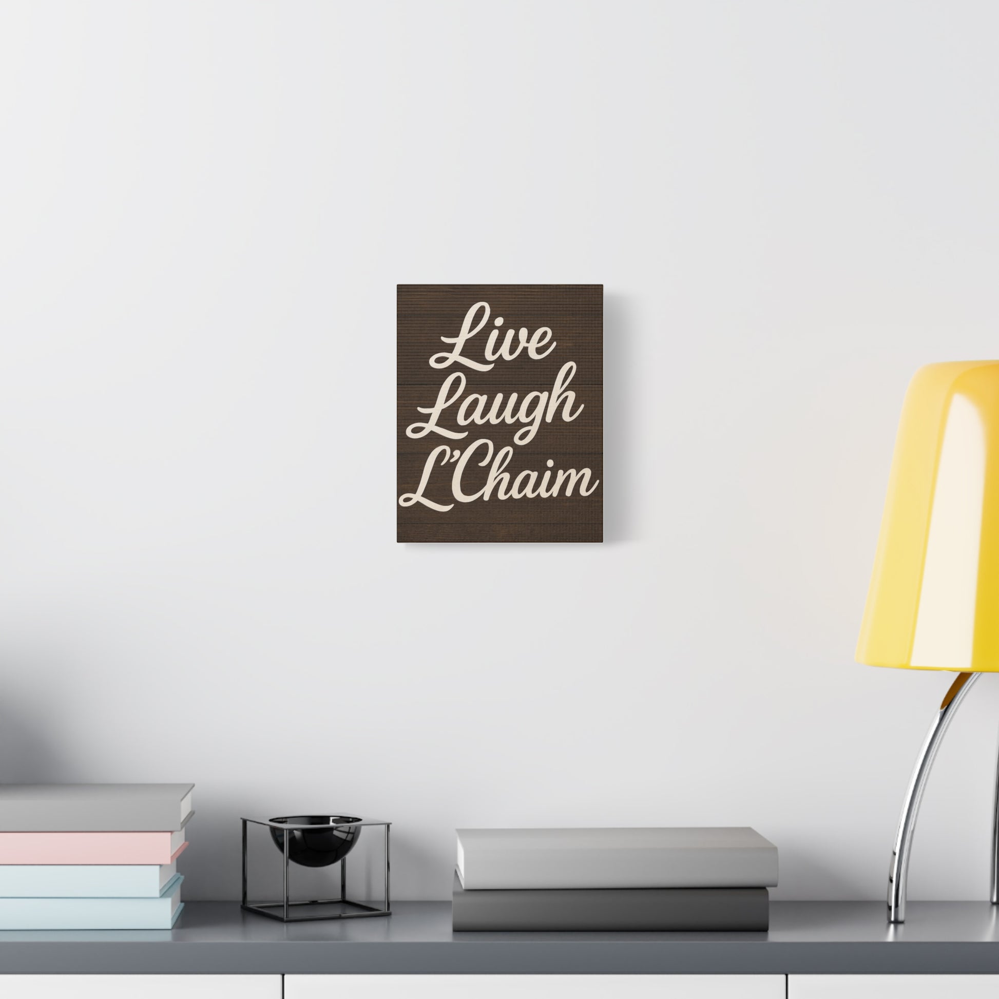 Decorative wall art with 'Live Laugh L'Chaim' text on a white wall above a desk.