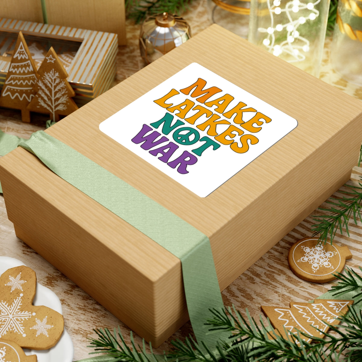 Wooden gift box with a colorful 'make latkes not war' sticker on a festive background with cookies and greenery.