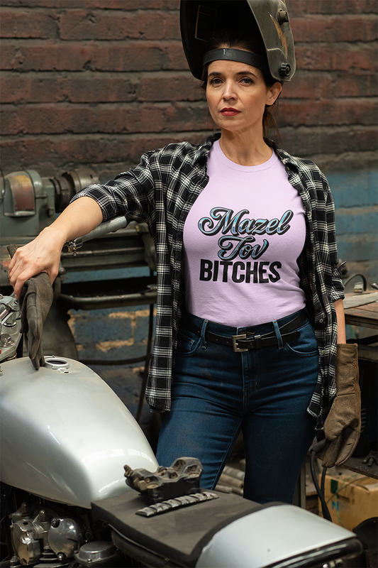 Person wearing a t-shirt with 'Mazel Tov Bitches' text in a workshop setting