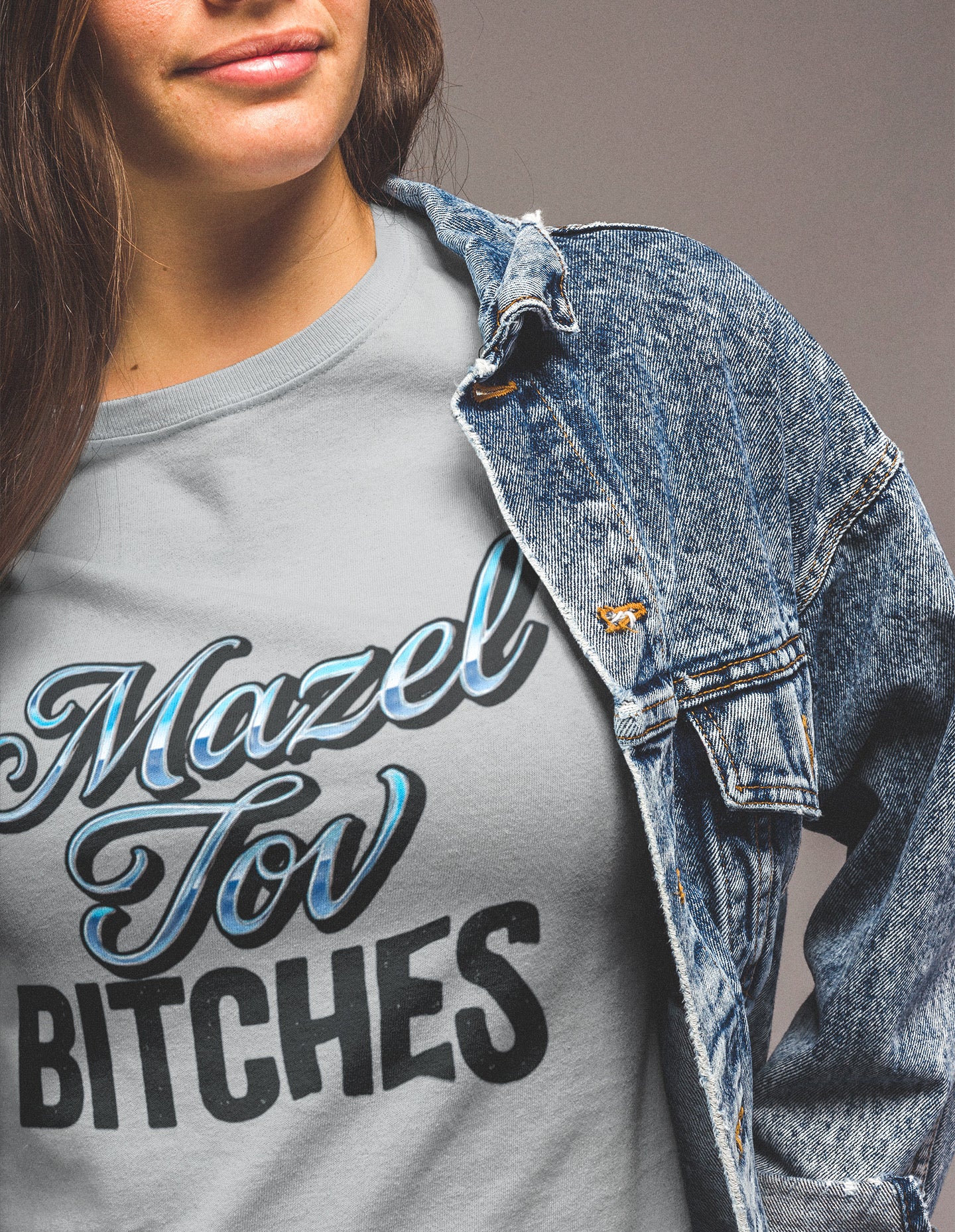 Person wearing a gray t-shirt with 'Mazel Tov Bitches' text and a denim jacket.