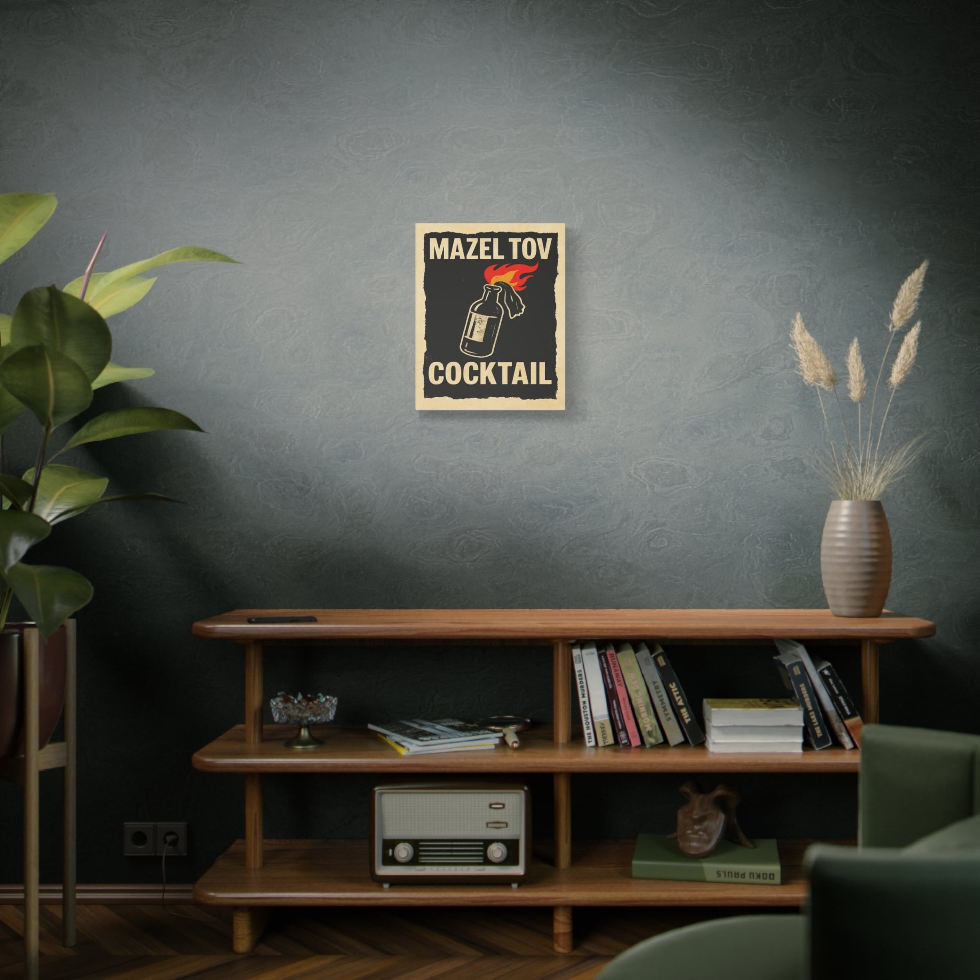 Room interior with a wooden shelf, books, a plant, and a decorative 'mazel tov cocktail' poster on a dark wall.